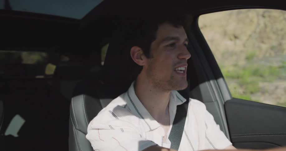 A couple laughing and singing together while listening to music on a car trip