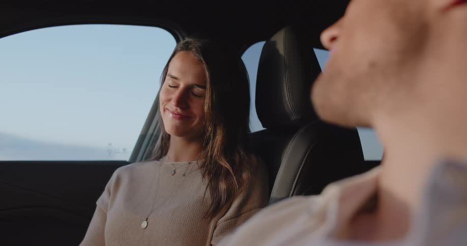 A young couple sitting on a car looking at each other