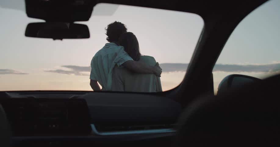 A couple are hugging while watching the sunrise