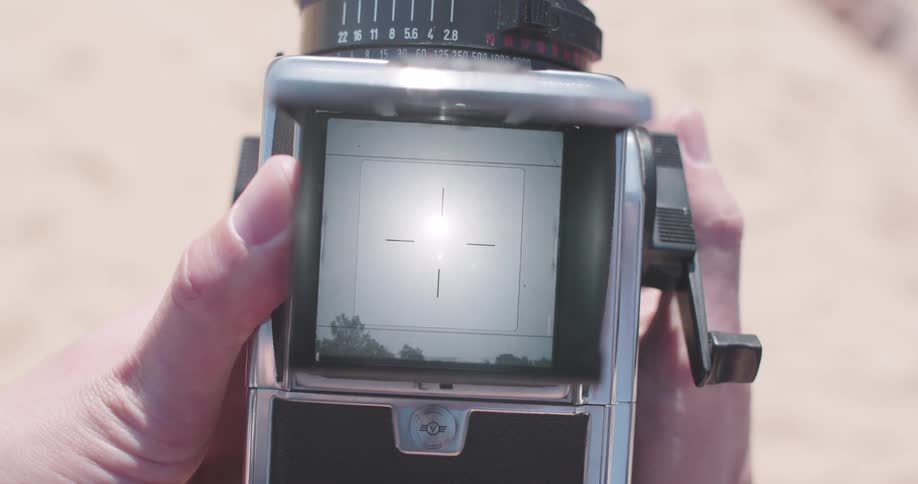Hand holding a camera with a viewfinder and setting it