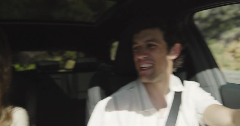 A young couple parked on the side of a road talking and laughing