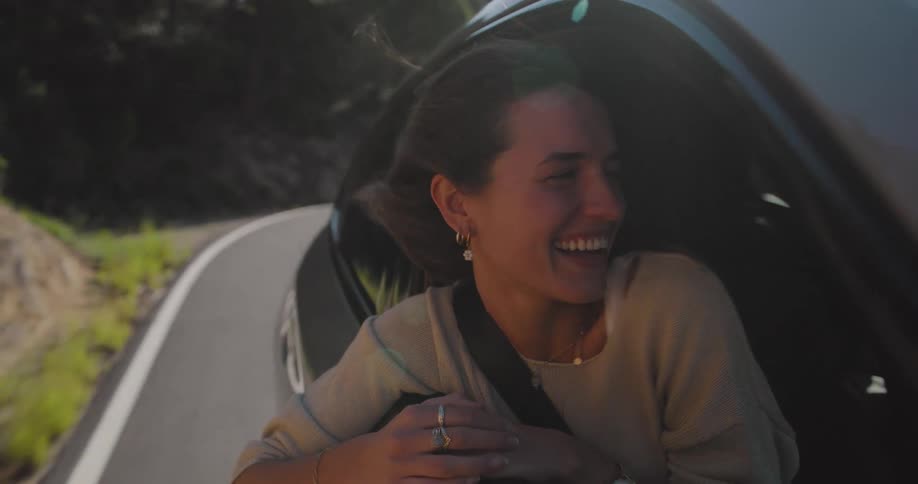 Woman enjoying in the front window of a moving vehicle in natural environment