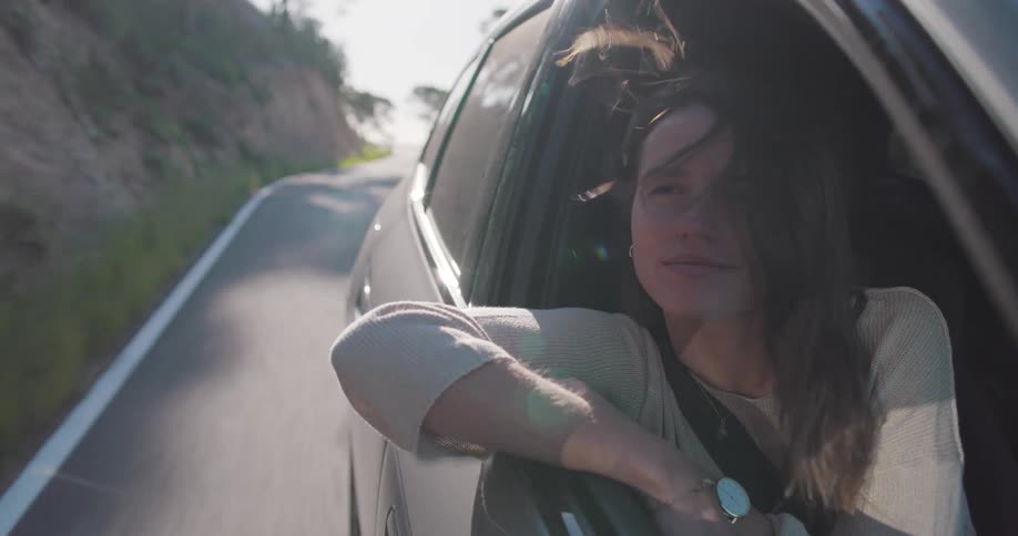 A woman smiles while looking out of a cars passenger window
