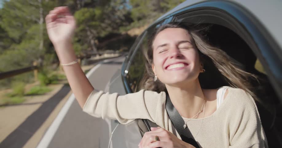 A woman laughing in a car as it travels on a coastal road