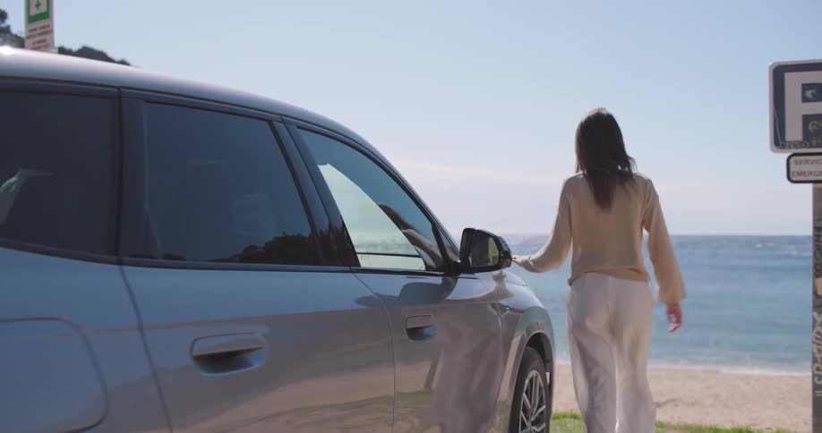 Friends get out of car parked near beach and stand together looking at the ocean