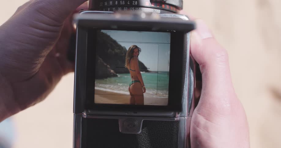 Viewfinder of a camera taking a photo of a young woman on the beach