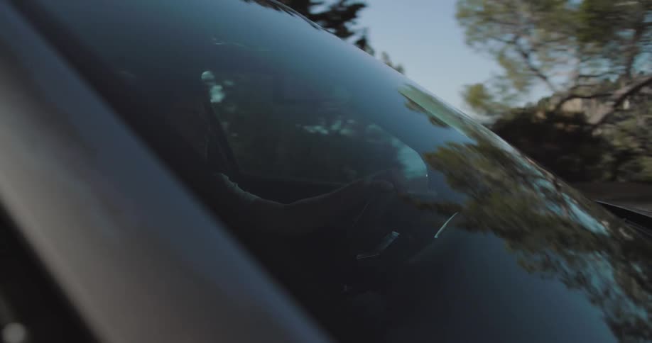 Trees reflect on the windshield of a vehicle driving on the countryside