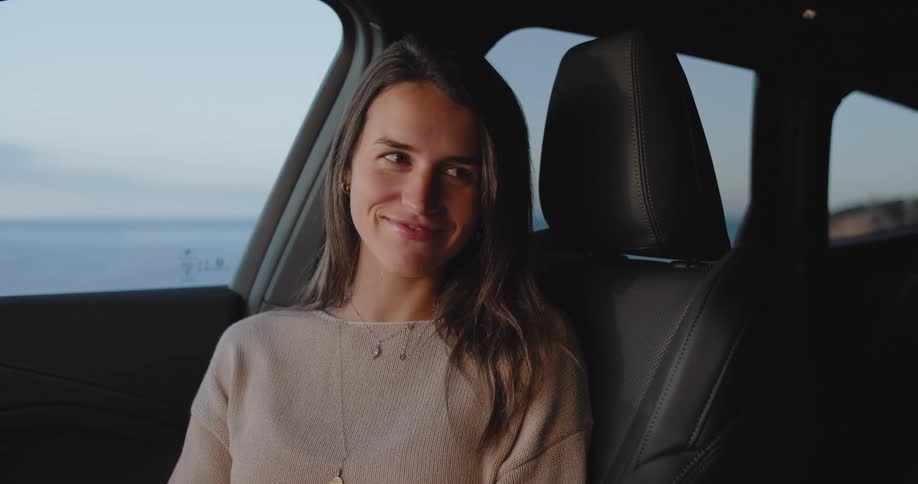 Woman sitting in the front passenger seat looking to the side and smiling