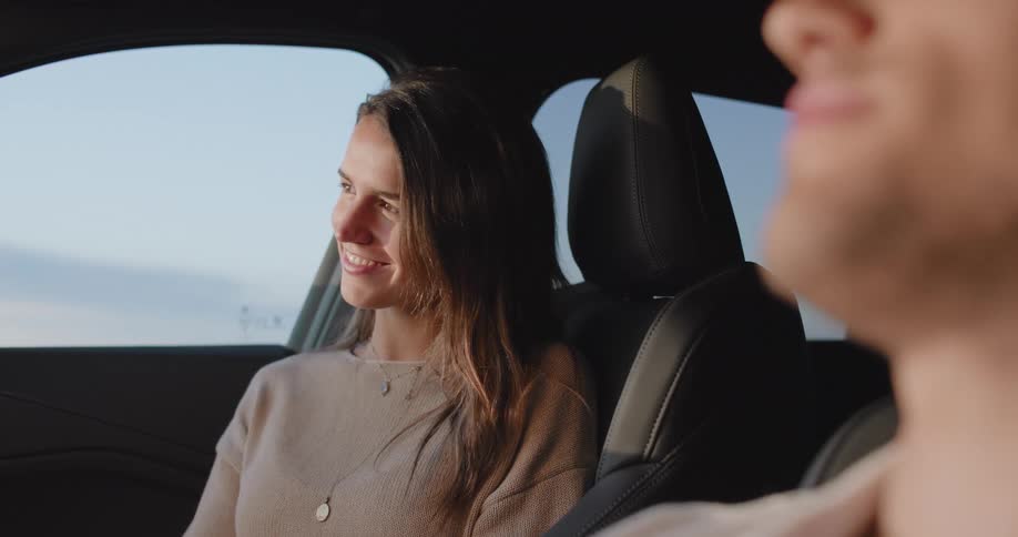 A young couple sitting on a car look at each other and smile