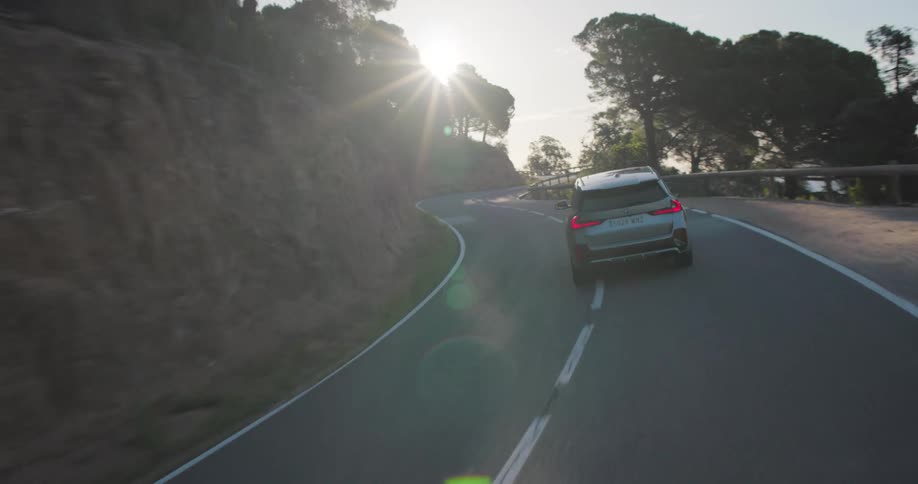 Gray bmw suv driving along a curvy asphalt in a natural environment