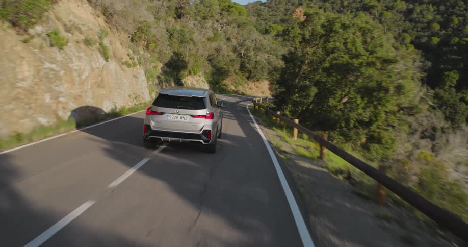 Bmw suv driving along a curvy road in a natural environment