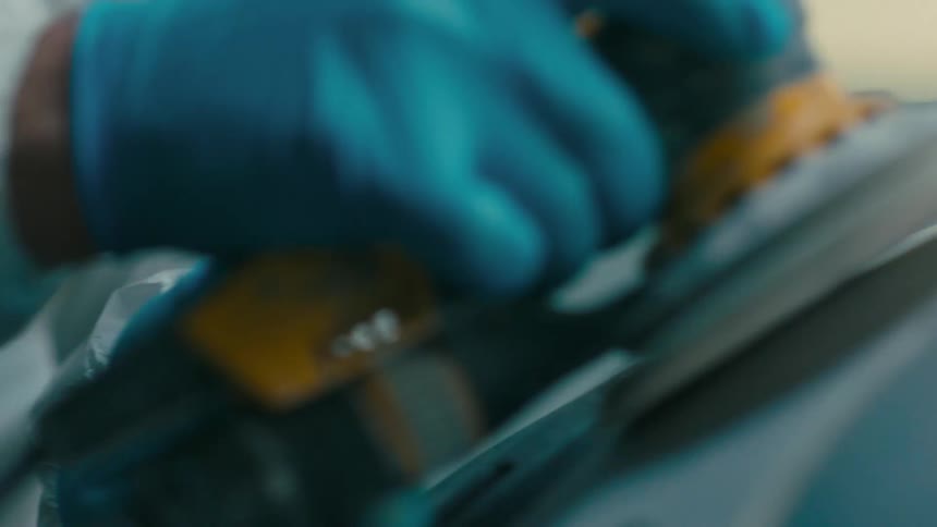 Man with protective mask concentrated using a scraping machine on a metal surface