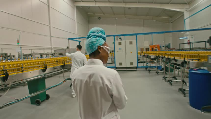Two factory workers talking in front of a vegetable oil production line