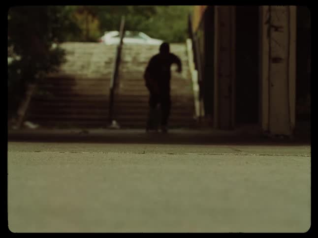 Silhouette of a boy running and jumping onto a skateboard