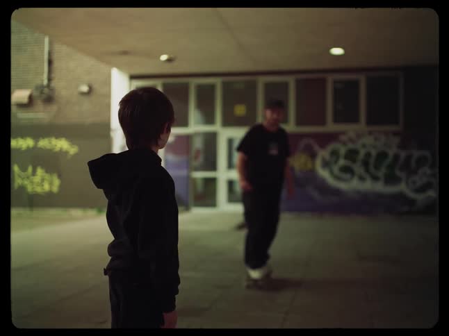 A teenager fist bumps a child as he skateboards by