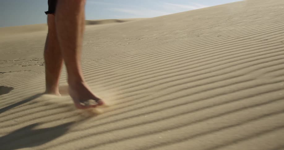 A man is hiking in the deep sand