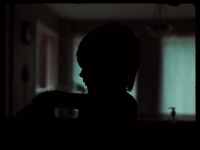 Silhouette of a young woman moving around a dimly lit room