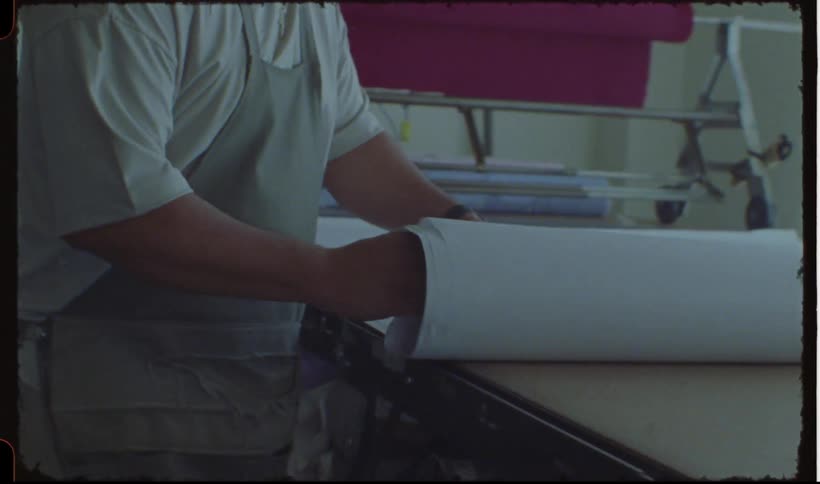 A person rolling a large sheet of paper on a flat surface