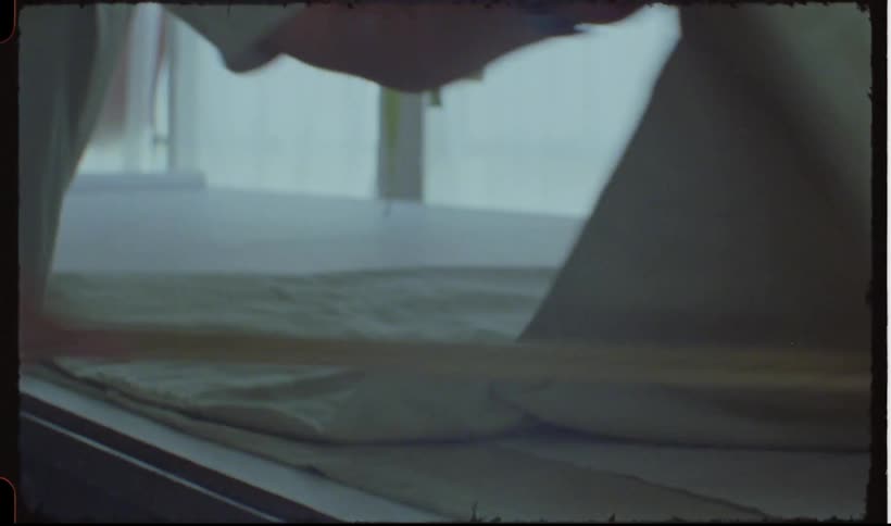 Man working in a laundry service folds a sheet with a stick