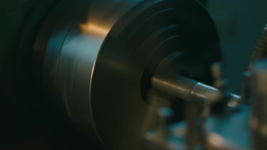 Side portrait of a woman with protective glasses concentrated while using a metalworking machine