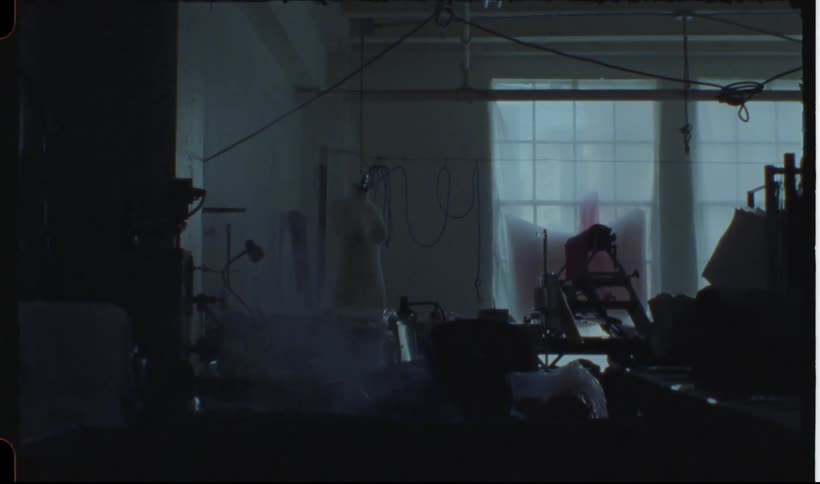 Silhouette of a seamstress ironing a piece of cloth in a dimly lit workshop