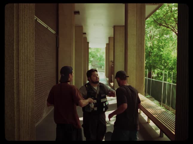 A security guard stops a couple of teenagers on a building