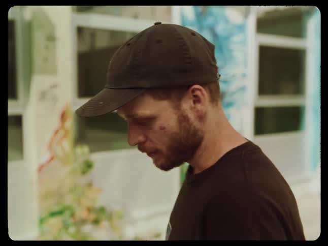 A man is standing in front of a wall covered in graffiti