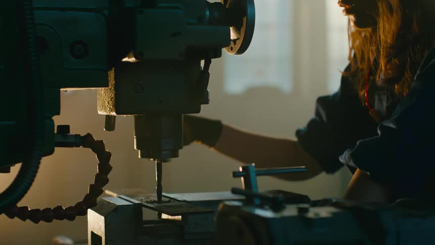 Woman with protective glasses handling a metallurgical machine with concentration