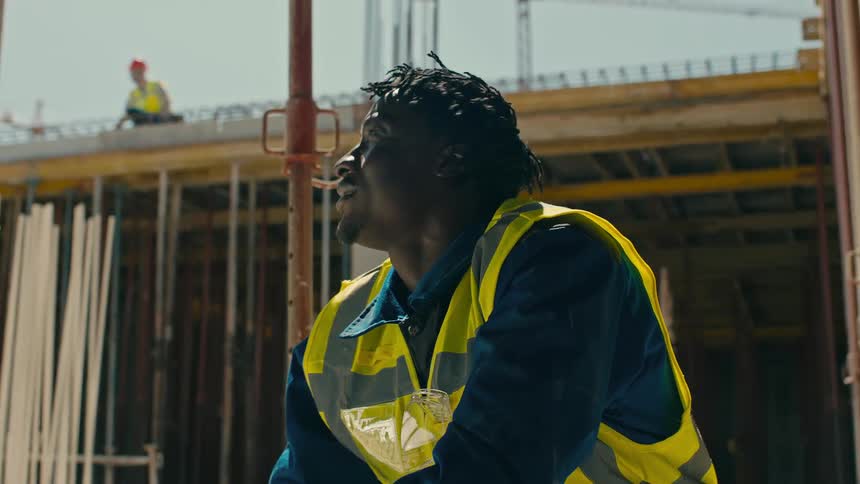 Portrait of a man taking off his sweaty hard hat and standing up at a construction site