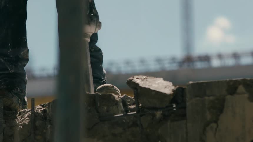 Construction worker jack hammering a hole in the asphalt outdoors