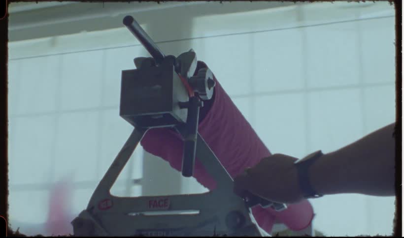 A man moving a roll of fabric over a table
