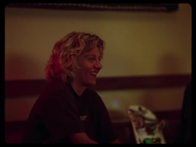Young man and smiling woman sitting next to a skateboard