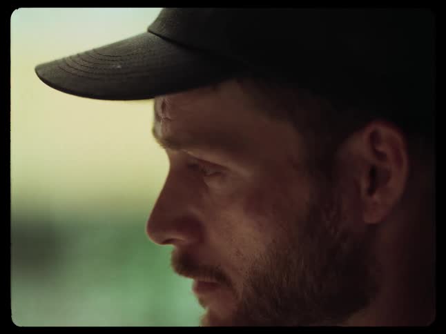 Side portrait of a man with a beard and a cap in an outdoor environment