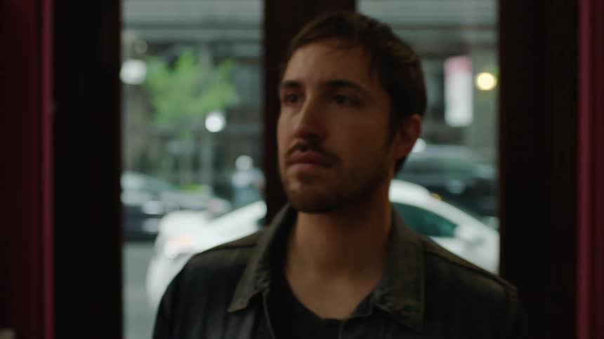 A man walks through a shop door and then stands and looks around