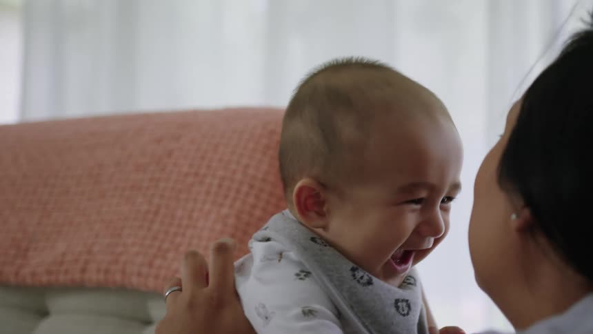Mother holding and playing with her baby son