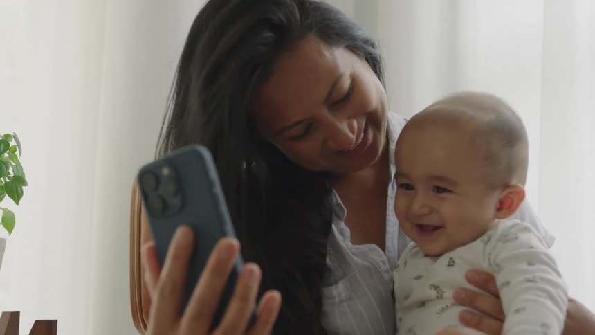 A mother takes her babys photo with a cell phone