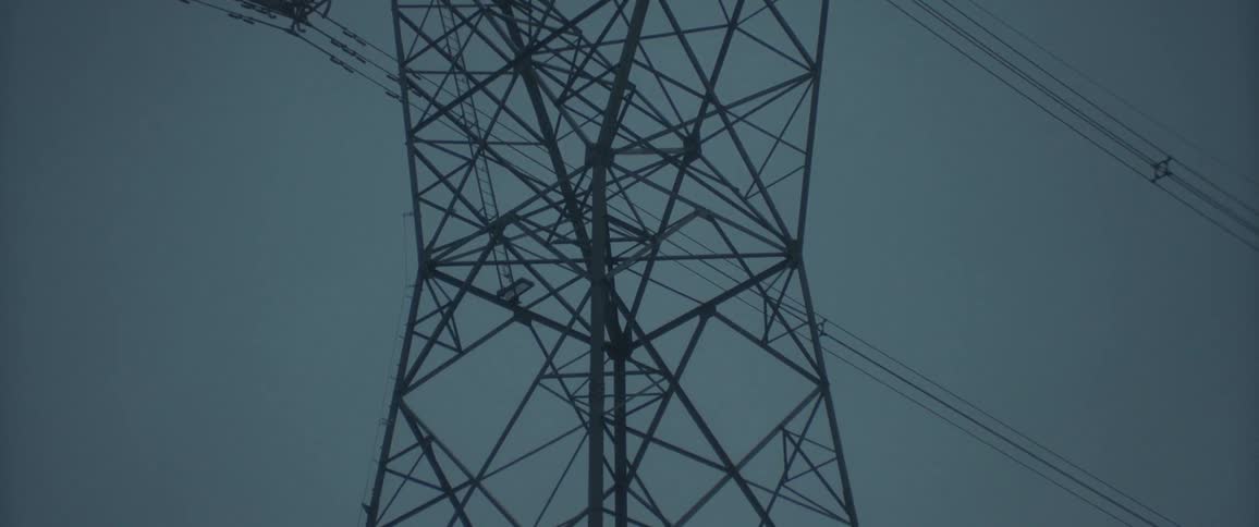 An electricity pylon under an dark overcast sky