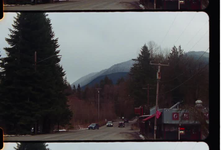 Vehicles traveling along a paved road with trees and mountains around
