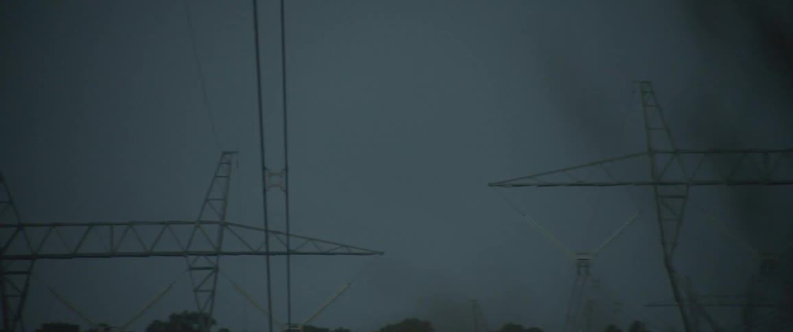 A dark overcast sky with silhouettes of electricity pylons