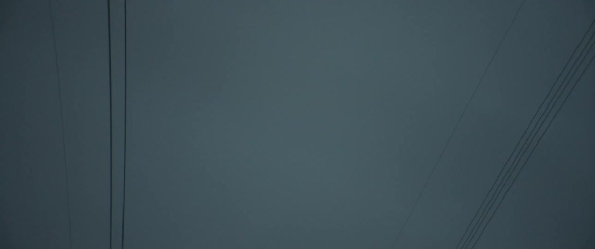 Overhead power lines under an overcast sky at dusk