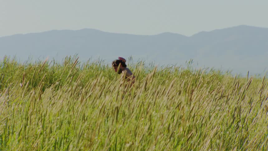 Man without a shirt dancing sensually and artistically on a hill with the silhouette of mountains in the background