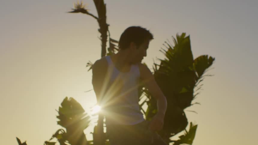 A man dancing in front of trees with the sun behind them