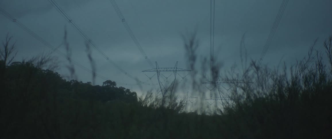 The high voltage power lines hum with electricity silhouetted against a starry night sky