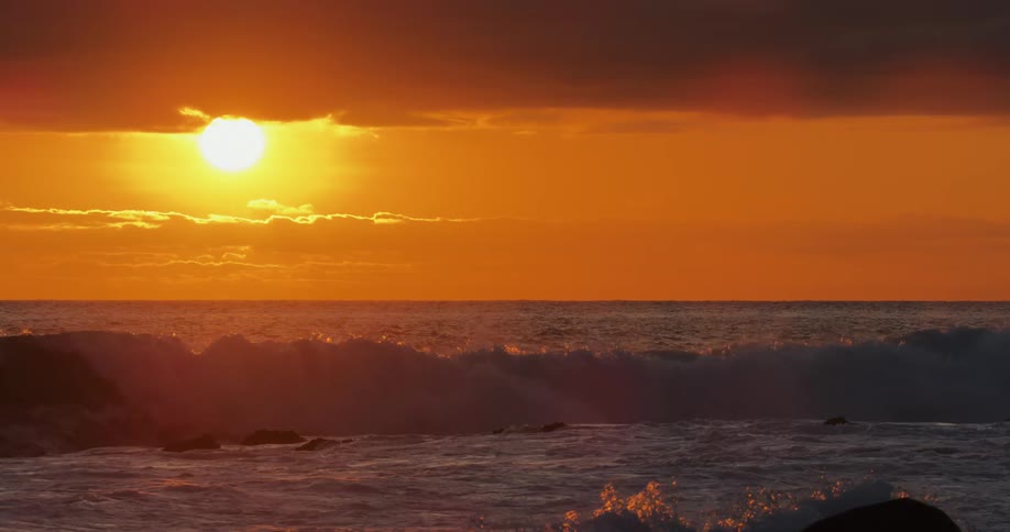 Beach with waves in a reddish sky with a prominent sun
