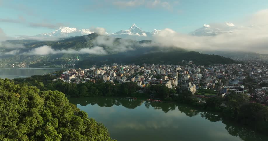 Aerial panorama of an urban city by a lake with snowcapped mountains on the horizon