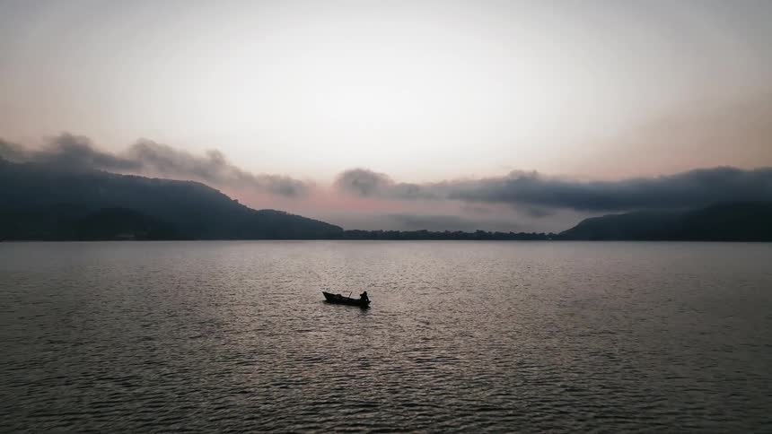The small sailboat with white sails glides across the blue water at sunset