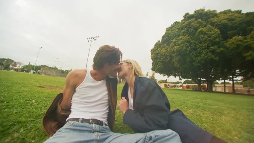 Loving couple sitting and kissing in a park