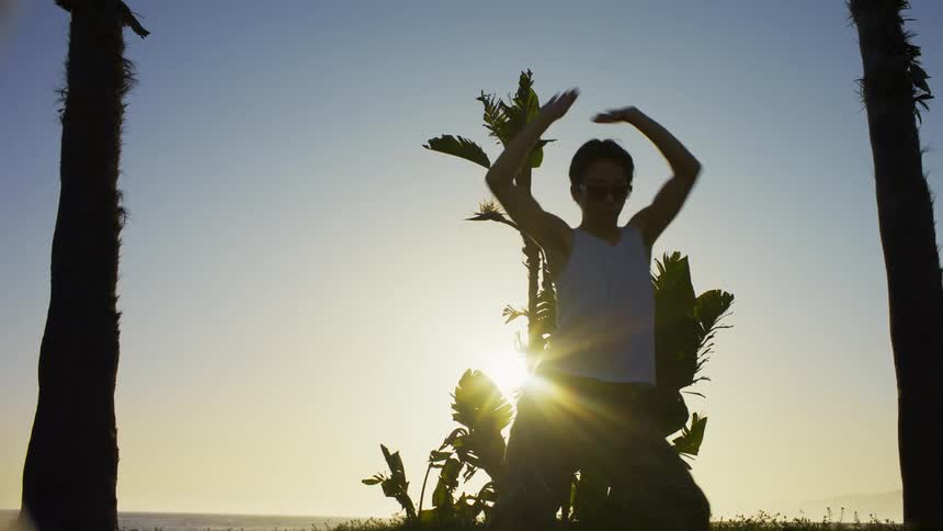 Man in an openair environment with palm trees around him dancing
