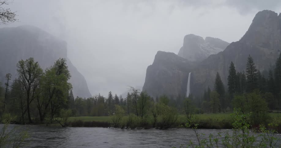 A waterfall drops water on the side of a large mountain