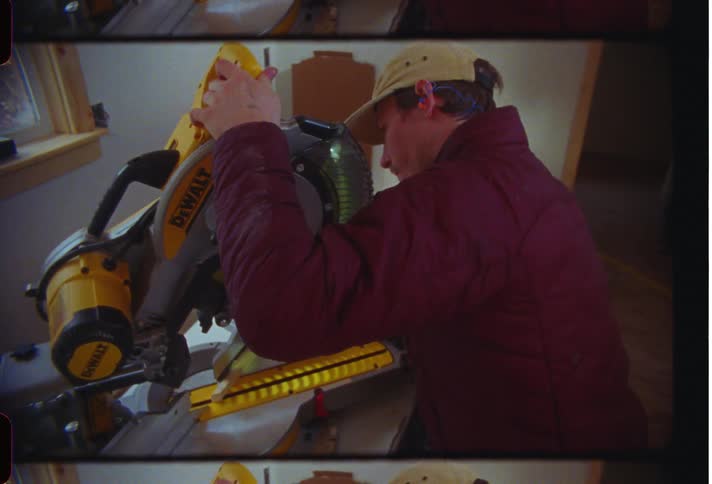 A man manipulates a large saw on a table in a room